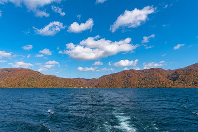 Scenic view of sea by mountains against blue sky