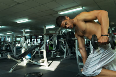 Shirtless man exercising at gym