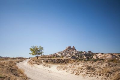 Dirt road in desert against clear sky