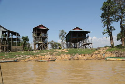 House by lake and buildings against clear sky