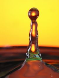 Close-up of water drops on glass against orange sky