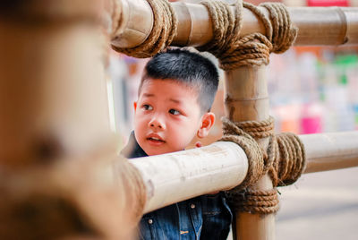 Thoughtful boy standing behind wooden fence