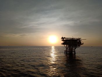 Silhouette ship in sea against sky during sunset