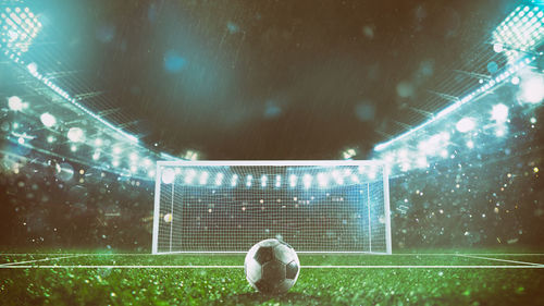 Digital composite image of soccer ball on field at night