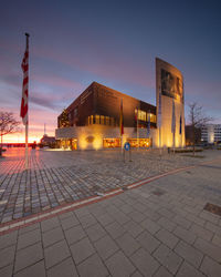 Illuminated building against sky at sunset