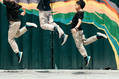 Friends jumping against wall
