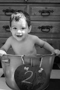 Portrait of cute smiling baby boy sitting in container