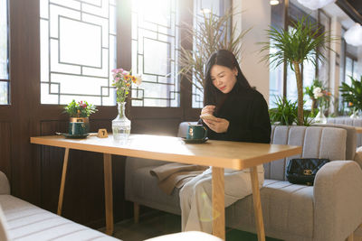 Portrait of young woman sitting on table at home