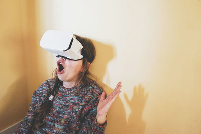 Side view of woman wearing hat standing against wall