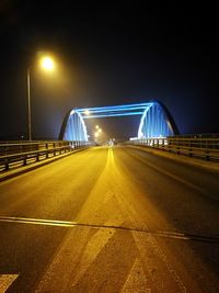 Illuminated road against sky at night