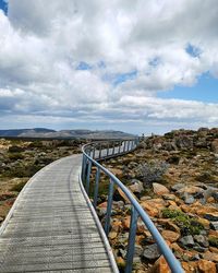 View of bridge leading towards landscape against sky