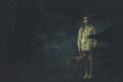 Woman standing by trees in forest