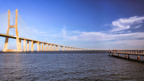 Bridge over river against cloudy sky