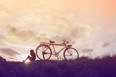 Silhouette bicycle on field against sky during sunset