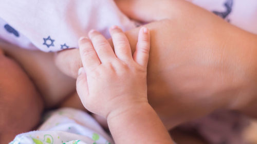 Close-up of baby hand on bed