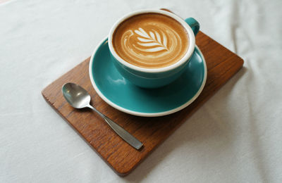 High angle view of  hot cappuccino white coffee cup with heart shape latte art on table at caff 