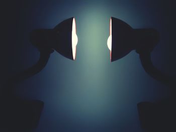 Low angle view of illuminated light bulb against wall