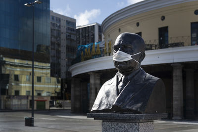 Monument statue in mercado modelo square with protective mask on face.