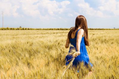 Rear view of woman walking on wheat field