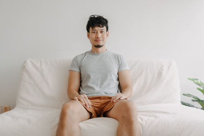 Young woman sitting on bed at home