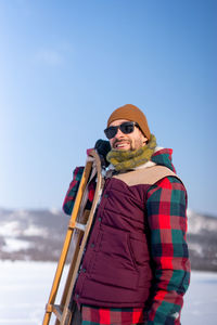 Man wearing sunglasses standing on snow against sky