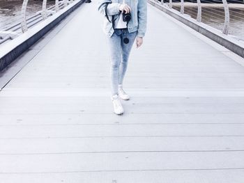 Low section of woman with camera standing on bridge