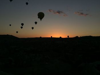 Silhouette of hot air balloons against sky during sunset