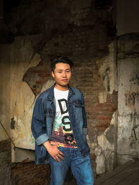 Portrait of young man standing against wall