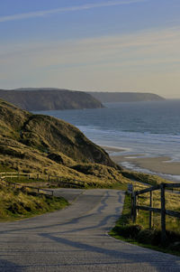 Scenic view of road by sea against sky