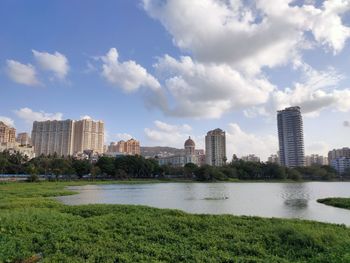 City buildings by river against sky