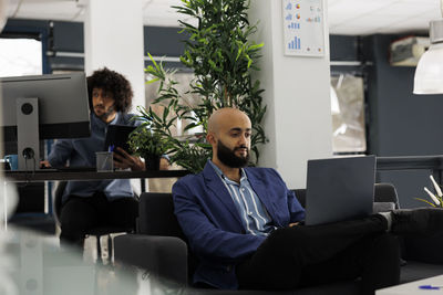 Side view of businessman using laptop at office