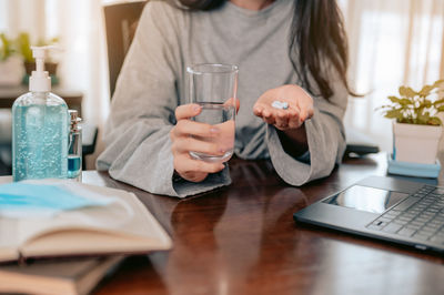 Midsection of woman using mobile phone while sitting on table