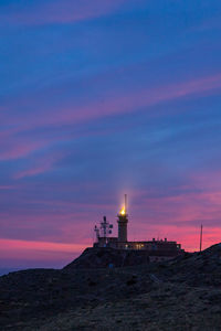 Lighthouse by sea against sky during sunset