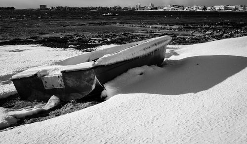 Deck chairs on sand at beach against sky
