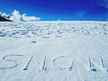 Text on snow covered land against blue sky