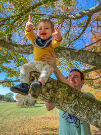 Happy boy smiling while standing against tree