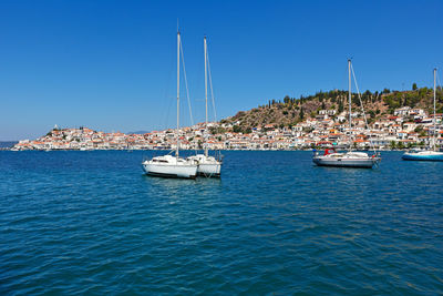 Sailboats sailing in sea against clear blue sky