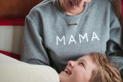 Midsection of woman with cheerful son lying at home