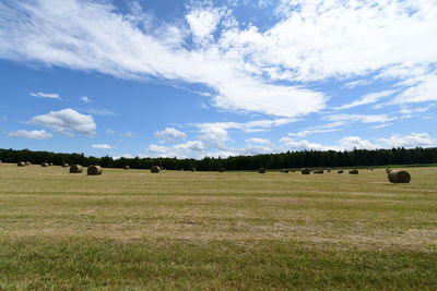 Hay bales on field against sky