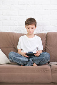 Portrait of boy sitting on sofa at home