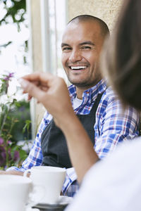 Smiling man with female coworker sitting at table outside cafe