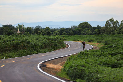 People riding bicycle on road against sky