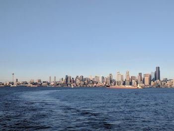 Sea by buildings against clear blue sky