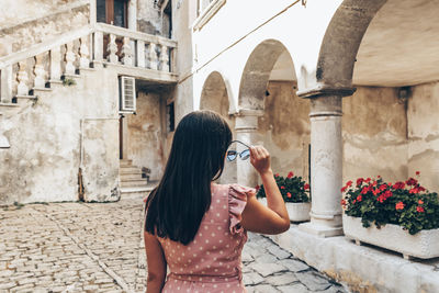 Young woman in summer dress putting on sunglasses.