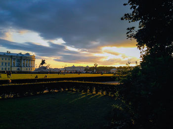 Scenic view of river by buildings against sky during sunset
