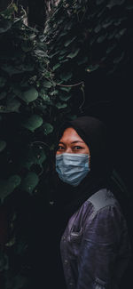 Portrait of young man wearing mask against plant