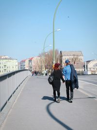 Woman walking on road against clear sky