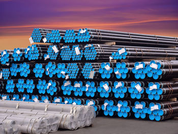 Stacking steel pipe in bundles at industrial yard for exporting.