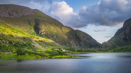 Mountains and black lake illuminated by sunlight at sunset in gap of dunloe, black valley, ireland