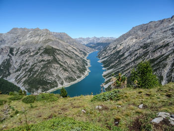 Scenic view of lake and mountains against clear blue sky